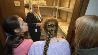 Viešbučio darbuotoja rodo mokinėms patalynės sandėlį